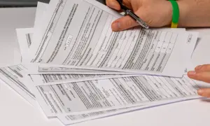 Dłoń z długopisem nad stosem dokumentów podatkowych PIT.