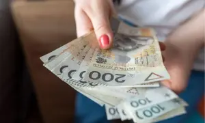 Dłoń trzymająca plik polskich banknotów 200 zł i 100 zł.