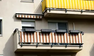 Dwa balkony z osłonami przeciwsłonecznymi: jeden żółto-biały, drugi beżowo-pomarańczowy.