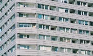 Szare bloki mieszkalne z wieloma oknami. Zastanawiasz się, ile kosztuje wynajem kawalerki w takim miejscu?