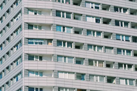 Szare bloki mieszkalne z wieloma oknami. Zastanawiasz się, ile kosztuje wynajem kawalerki w takim miejscu?