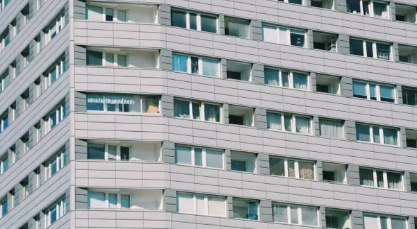 Szare bloki mieszkalne z wieloma oknami. Zastanawiasz się, ile kosztuje wynajem kawalerki w takim miejscu?